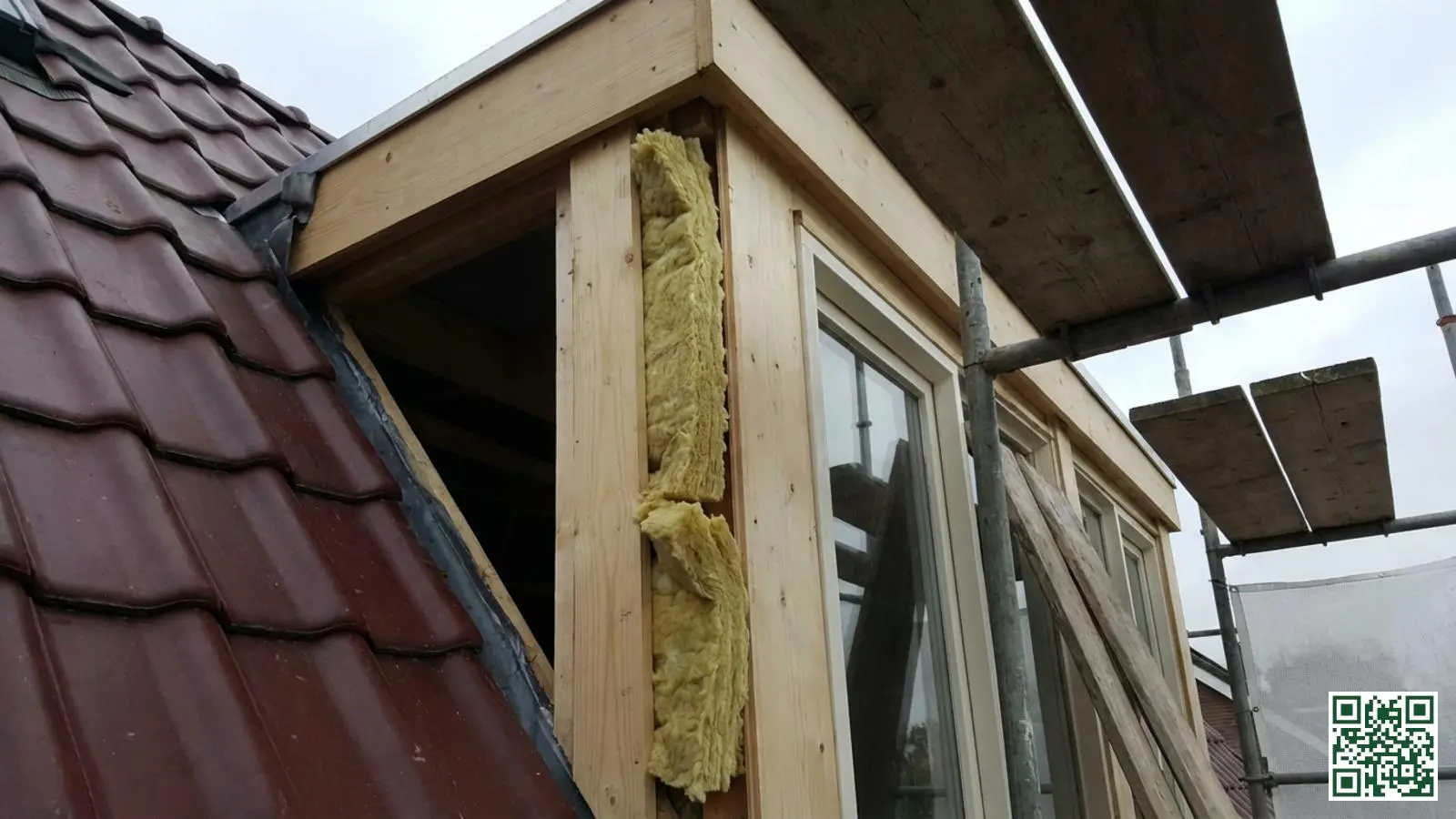 Detail van de aansluiting tussen een dakkapel en het schuine dak met zichtbaar isolatiemateriaal